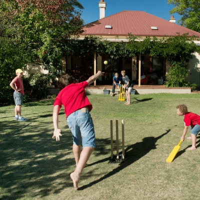 Boys playing cricket in backyard
